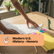Person working on a U.S. map with educational materials on a desk, labeled 'Modern U.S. History - Honors'.